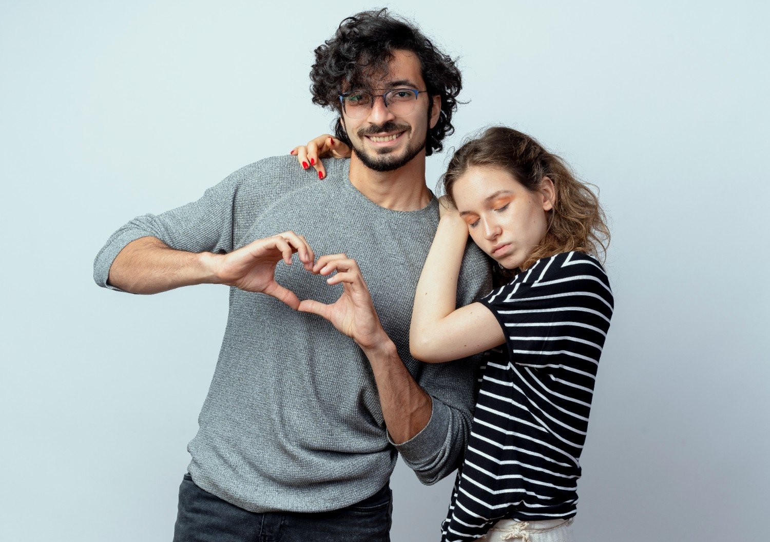 A smiling couple standing close together, forming a heart shape with their hands, symbolizing strong self-esteem and emotional connection in a healthy relationship.