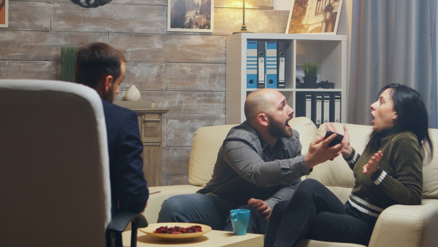 A couple argues emotionally during a session with a therapist, showing the challenges and raw emotions that can arise in couples therapy after infidelity.