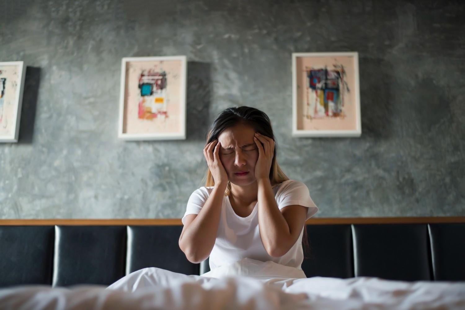 depressed-woman-with-headache-hand-holding-her-head-bed Experiencing Morning Anxiety